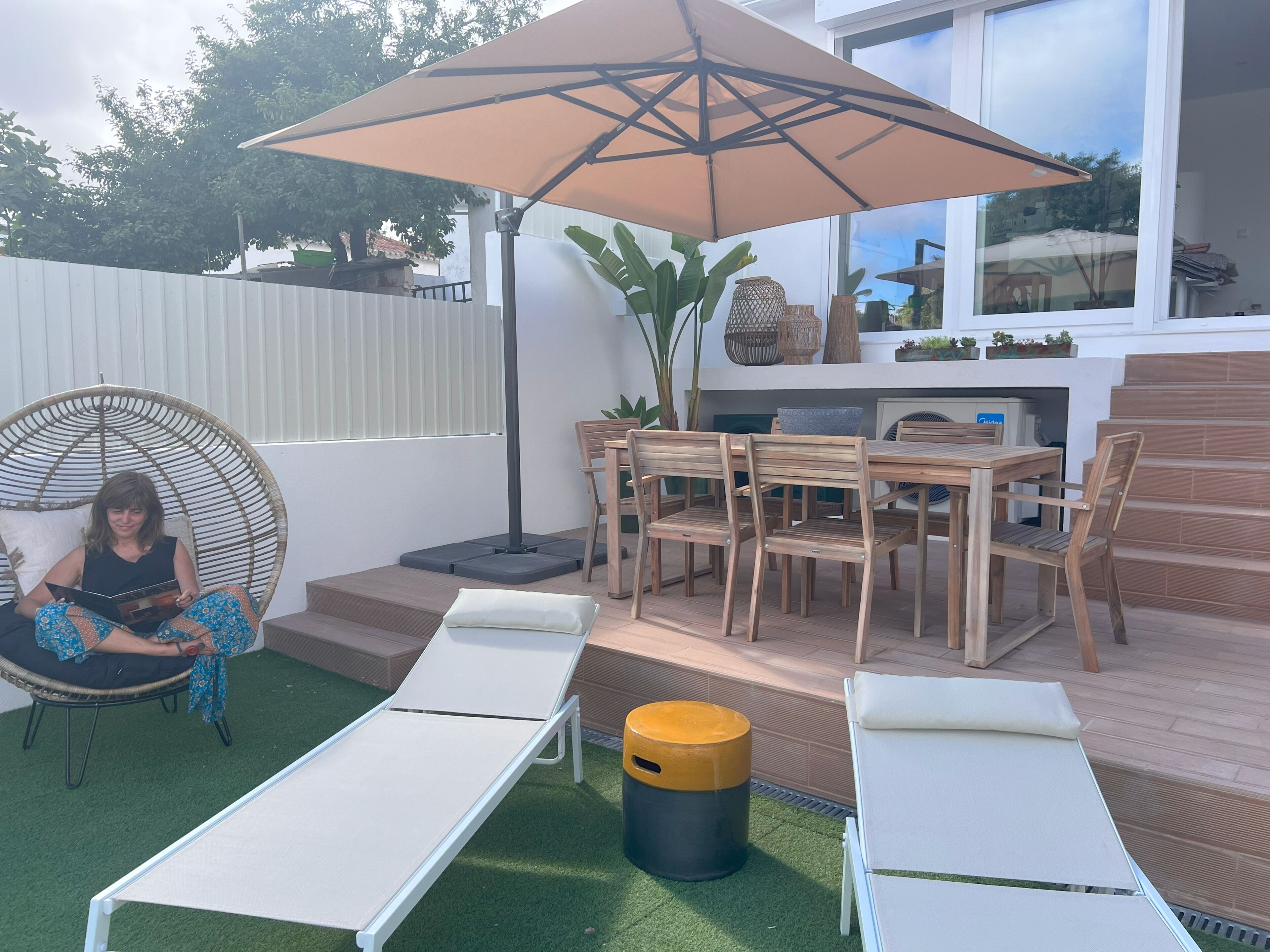 A patio with lounge chairs, a dining table, and a large umbrella.