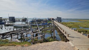 A wooden pier extending into a marshy area with boats docked nearby. - Comporta Sandy Villa, By Timecooler (Alcacer do Sal)