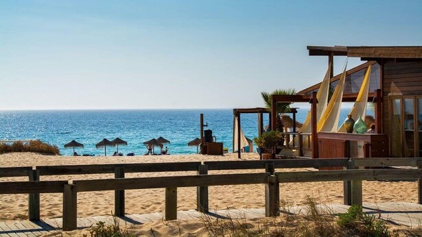 A beach view with a wooden structure and umbrellas. - Comporta Sandy Villa, By Timecooler (Alcacer do Sal)
