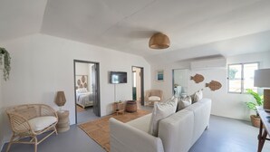 A spacious living room with a large sofa, a wicker chair, a flat-screen TV, and a large mirror. - Comporta Sandy Villa, By Timecooler (Alcacer do Sal)