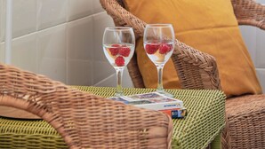 A wicker chair with a yellow cushion, a wicker lamp, and two glasses with fruit on a table. - Central & Sunny 2Br Apt Near Beach, By Timecooler (Setubal)