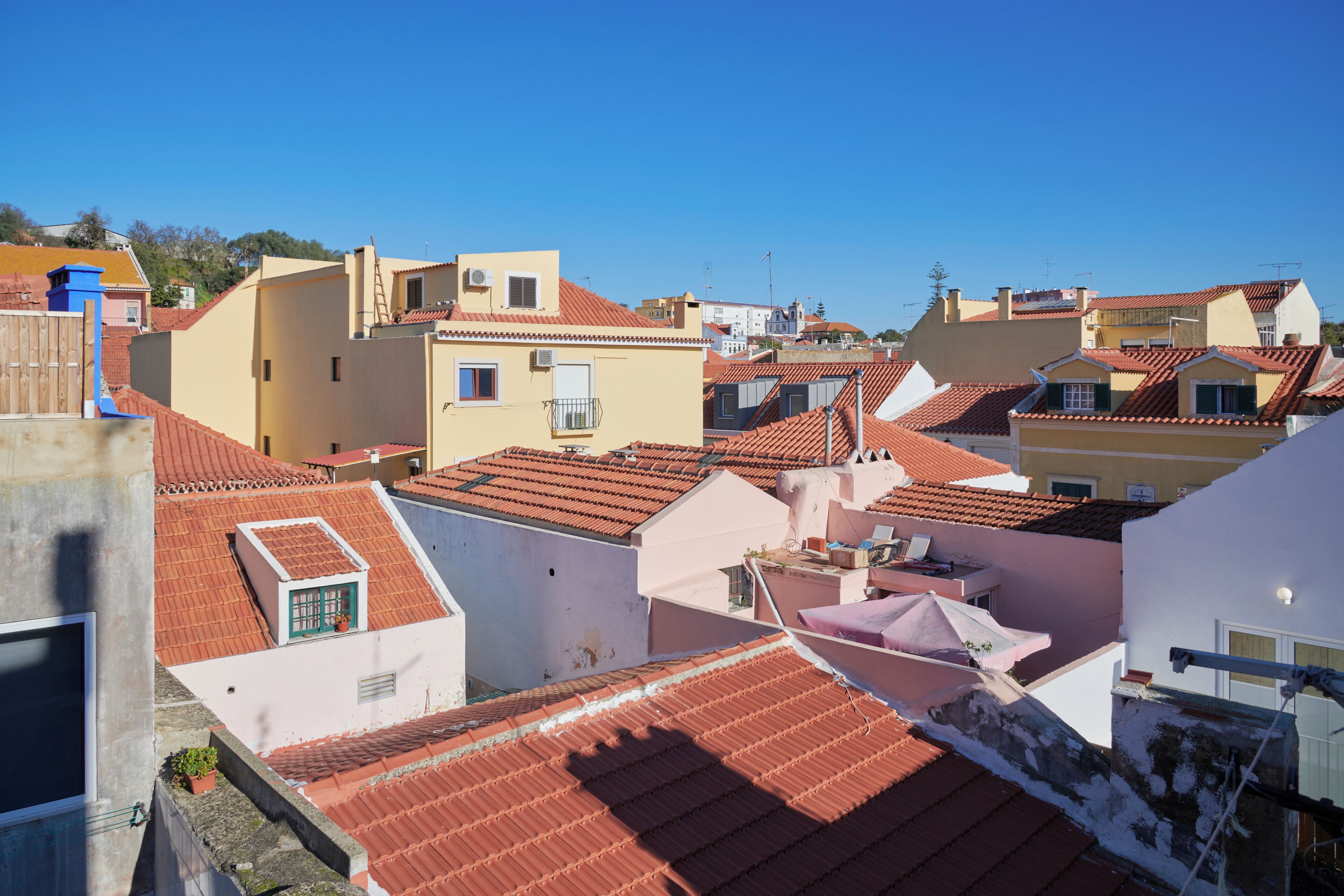 A residential area with red-tiled roofs, white and yellow buildings, and a clear blue sky.