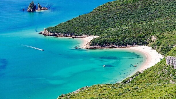A coastal landscape with a beach, clear turquoise waters, and green hills. - Central & Sunny 2Br Apt Near Beach, By Timecooler (Setubal)