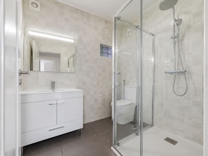 A modern bathroom with a glass-enclosed shower, a white vanity with drawers, and a mirror above the sink.