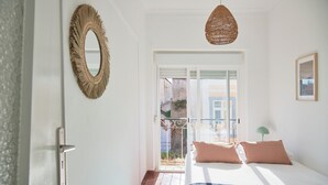 A bedroom with a bed, a hanging light fixture, a door, and a window. - Central & Sunny 2Br Apt Near Beach, By Timecooler (Setubal)