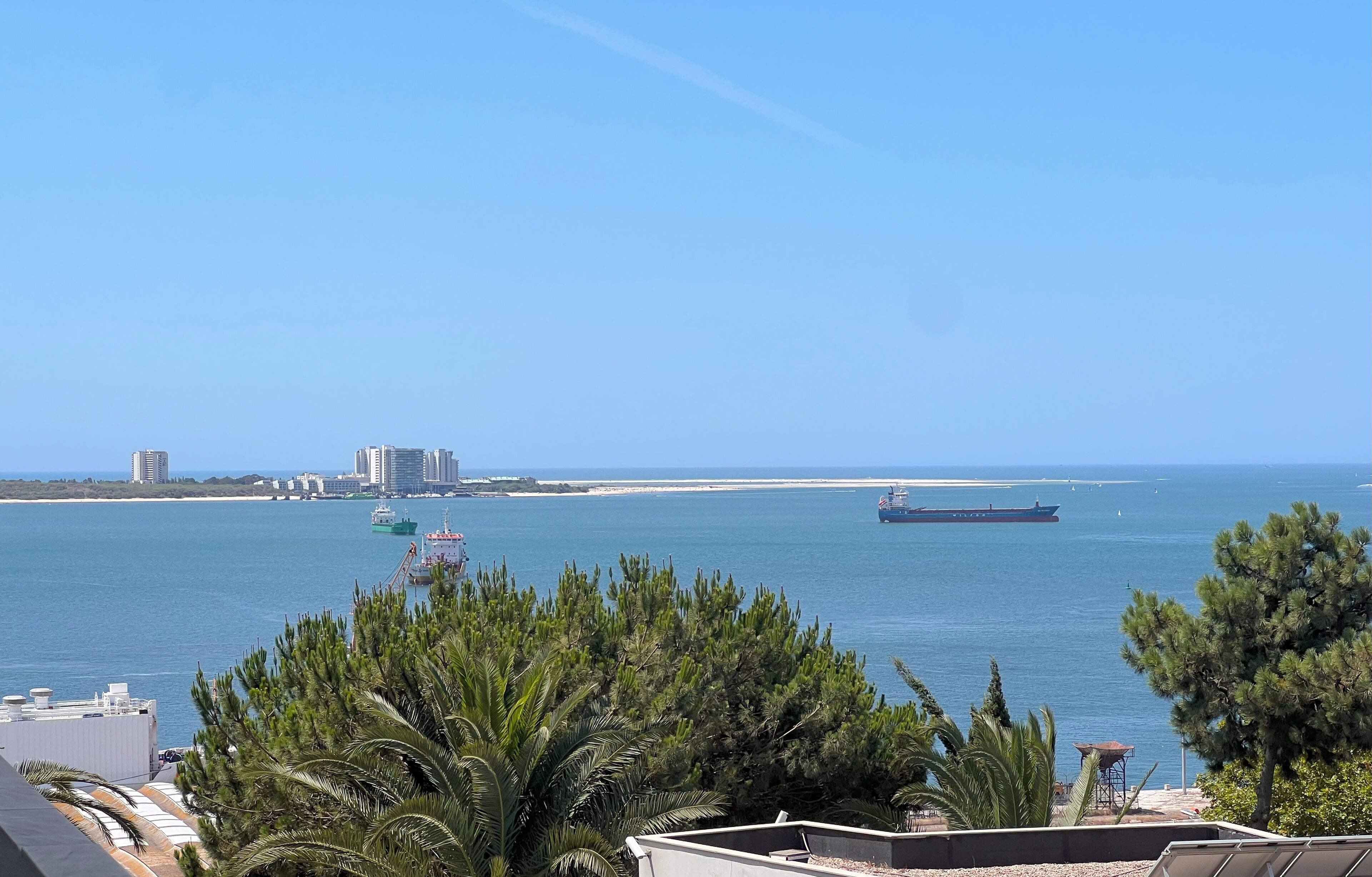 Une vue sur la côte, avec un grand navire, des bâtiments et un ciel dégagé.