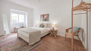 A bedroom with a bed, bedside tables, a hanging chair, a standing heater, and a window. - Spacious & Light Filled 4Br Apartment By Timecoler (Amadora)