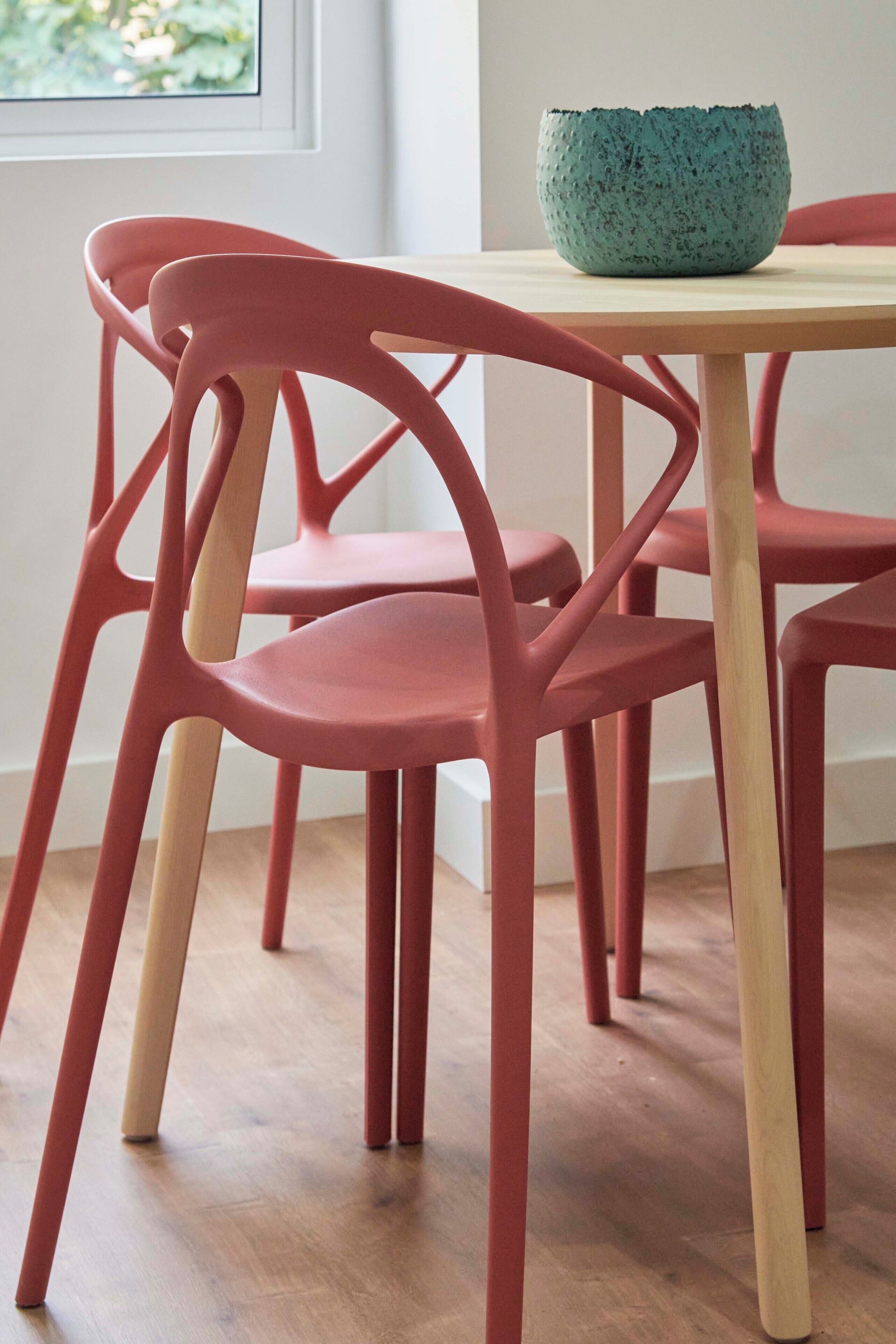 Un comedor con una mesa y sillas, un bol en la mesa y una ventana al fondo.