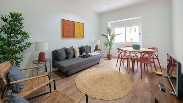 A modern living room with a sofa, chairs, a dining table, and potted plants. - Spacious & Light Filled 4Br Apartment By Timecoler (Amadora)