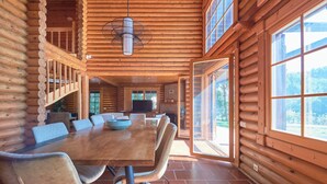 A log cabin with a large dining table, chairs, a staircase, and large windows. - Beach & Golf Retreat W Amazing Pool, By Timecooler (Almada)