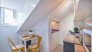 Una cocina compacta con comedor, ventana y horno empotrado.
