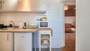 Una cocina compacta con microondas integrado, un lavabo y un refrigerador pequeño.