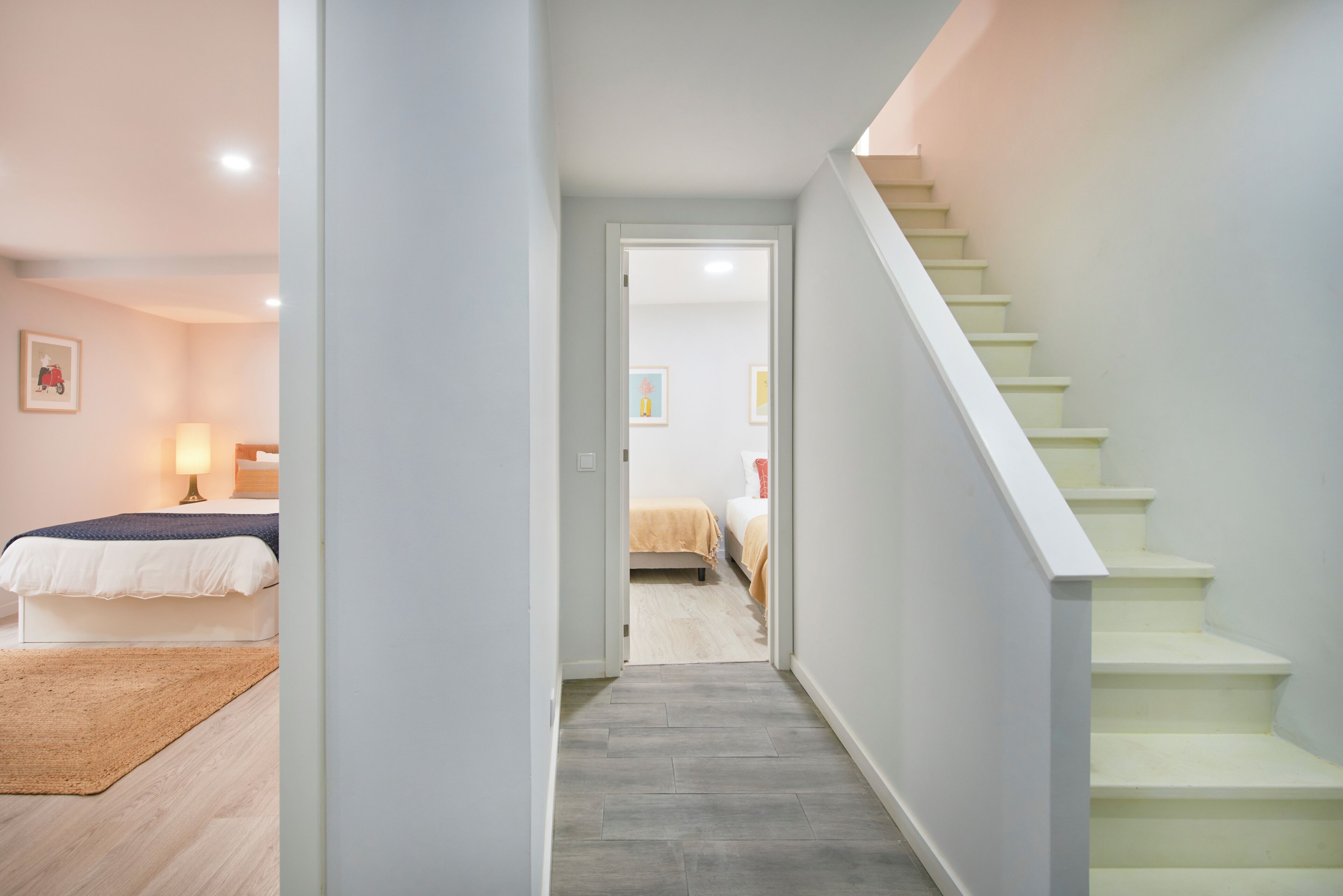 A hallway leading to a bedroom with a bed, a bedside table, and a lamp.