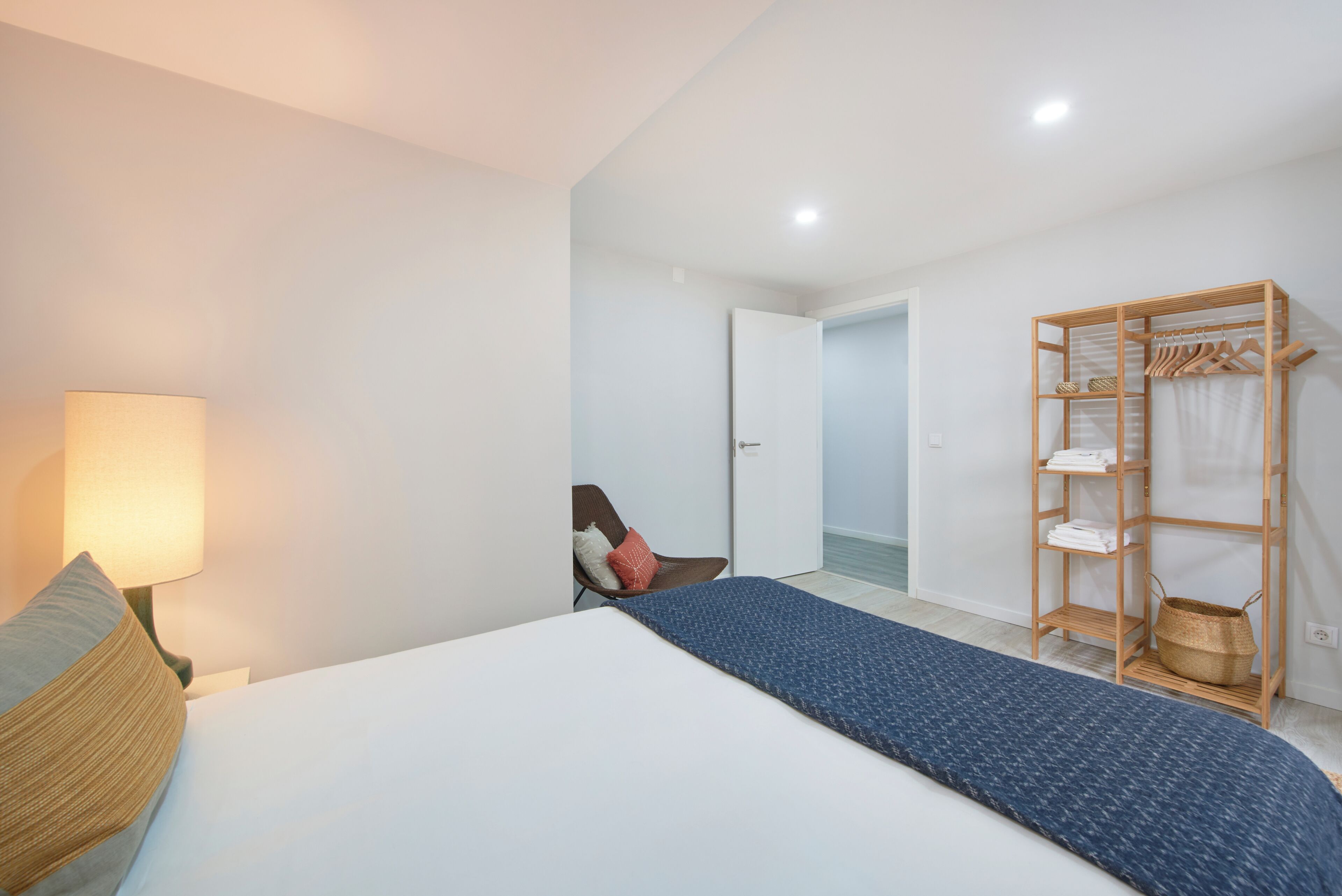 A bedroom with a bed, a chair, a wardrobe, and a lamp.