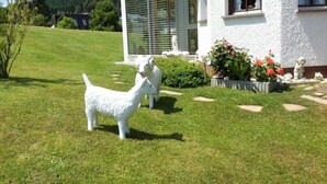 A white house with a large glass window and a garden with two white sculptures. - Holiday Apartment Schupp (Dachsberg)