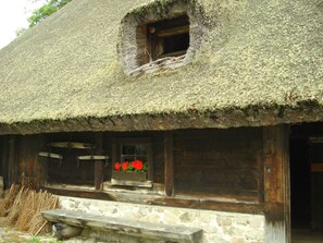 Un edificio rústico con techo de paja, base de piedra y ventanas de madera.