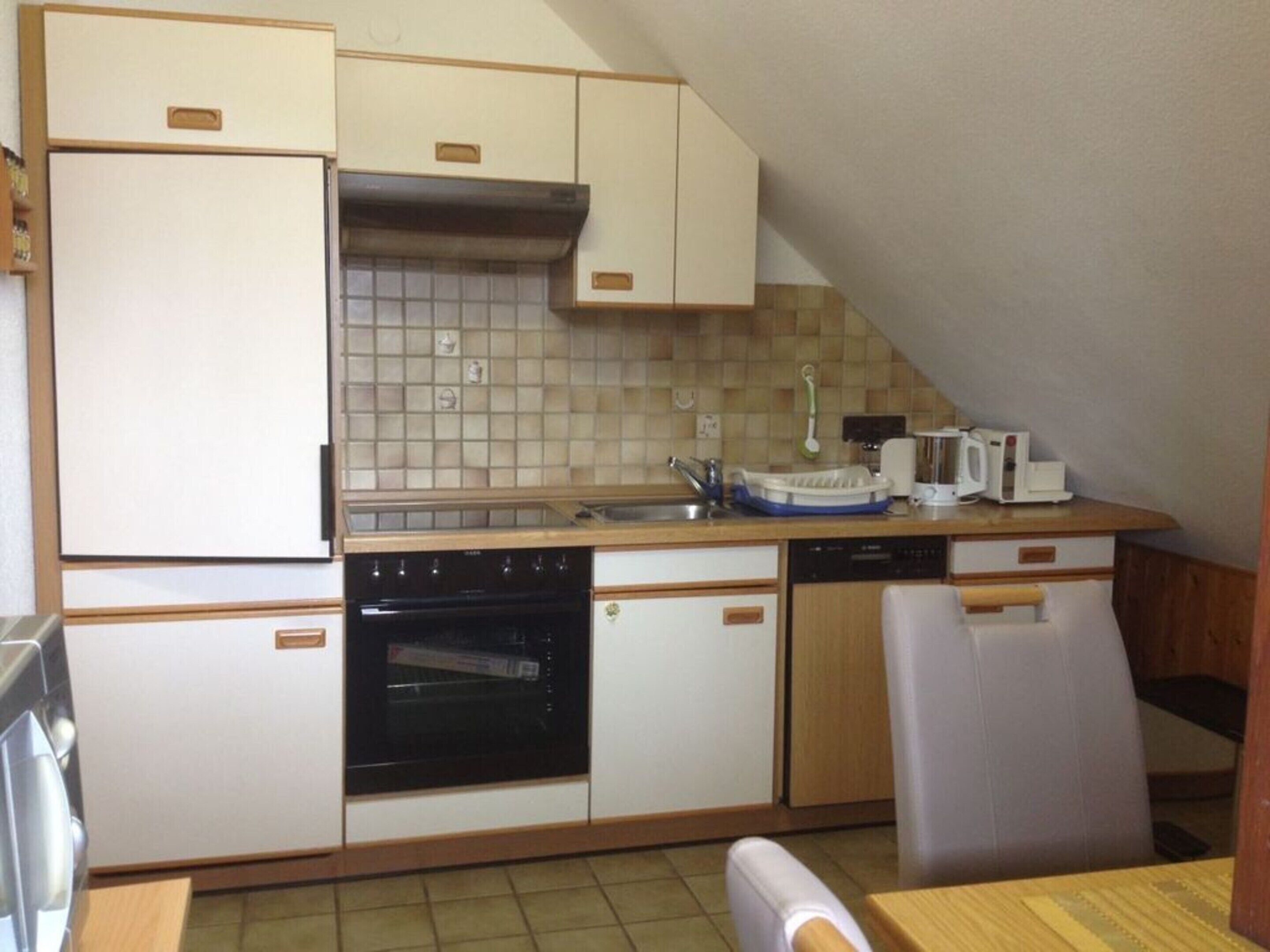 A compact kitchen with a dishwasher, oven, and a microwave on the countertop.