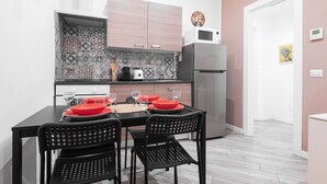 Una cucina moderna con un tavolo da pranzo per quattro persone, con sedie nere e piatti rossi.