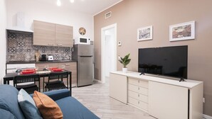 Un appartamento moderno con angolo cottura, zona pranzo e soggiorno con TV.