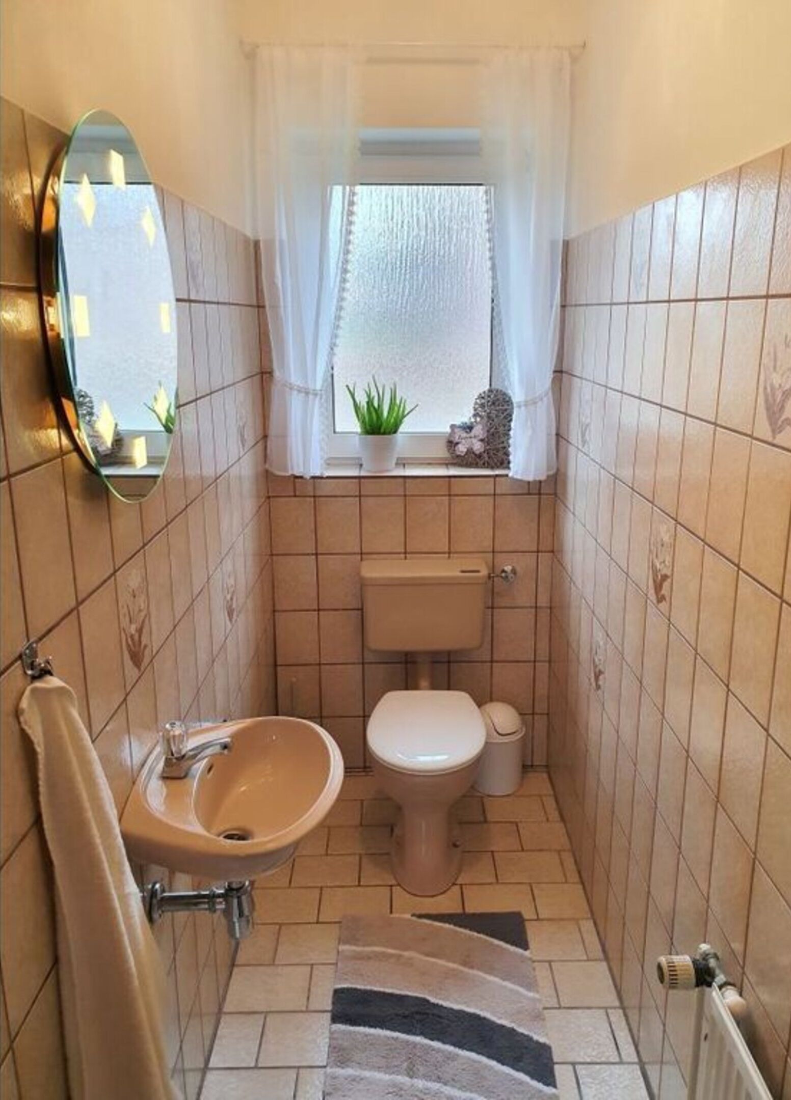 A small bathroom with a sink, toilet, and a mirror.