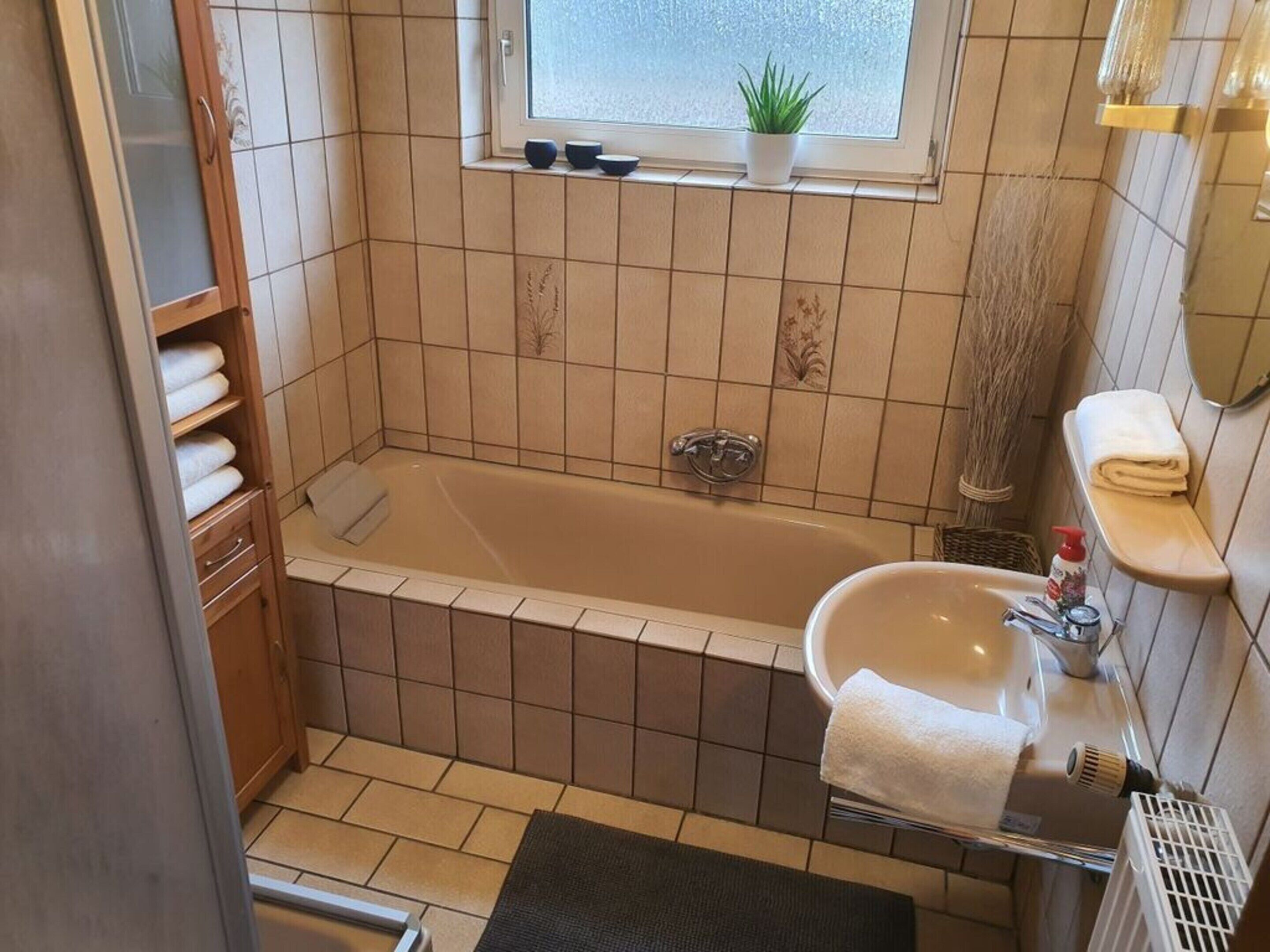 Un baño con bañera, lavamanos y ventana.