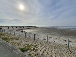 A beach with a fence, a row of colorful containers, and a clear sky. - Holiday Home Nordseegluck (Westerholt)