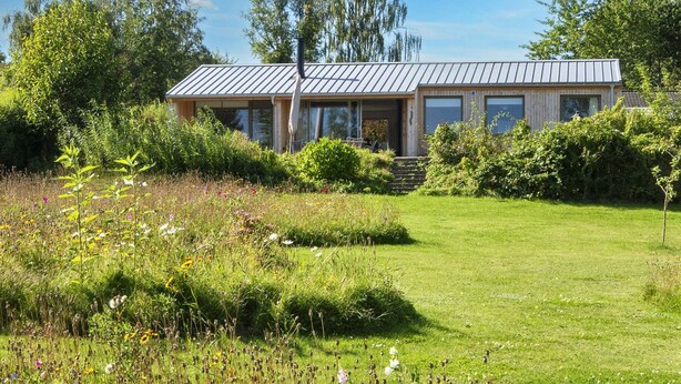 A modern house with a metal roof, surrounded by a well-maintained garden with various plants and flowers. - 4 Star Holiday Home in Ronde (Ronde)