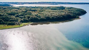 An aerial view of a coastal area with a large body of water, a forested peninsula, and a clear sky. - 4 Star Holiday Home in Ronde (Ronde)