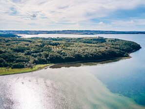 An aerial view of a coastal area with a large body of water, a forested peninsula, and a clear sky. - 4 Star Holiday Home in Ronde (Ronde)