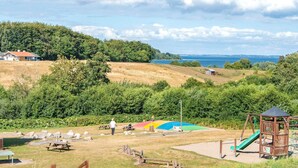 Ein Park mit Picknicktischen, einem Spielplatz und Blick auf das Meer.