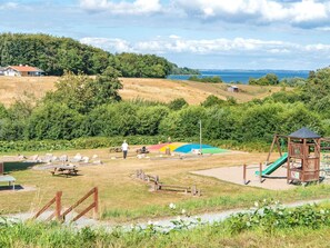 Ein Park mit Picknicktischen, einem Spielplatz und Blick auf das Meer.