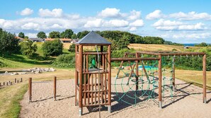Ein Spielplatz mit einer hölzernen Kletterkonstruktion und einer kleinen Schutzhütte.