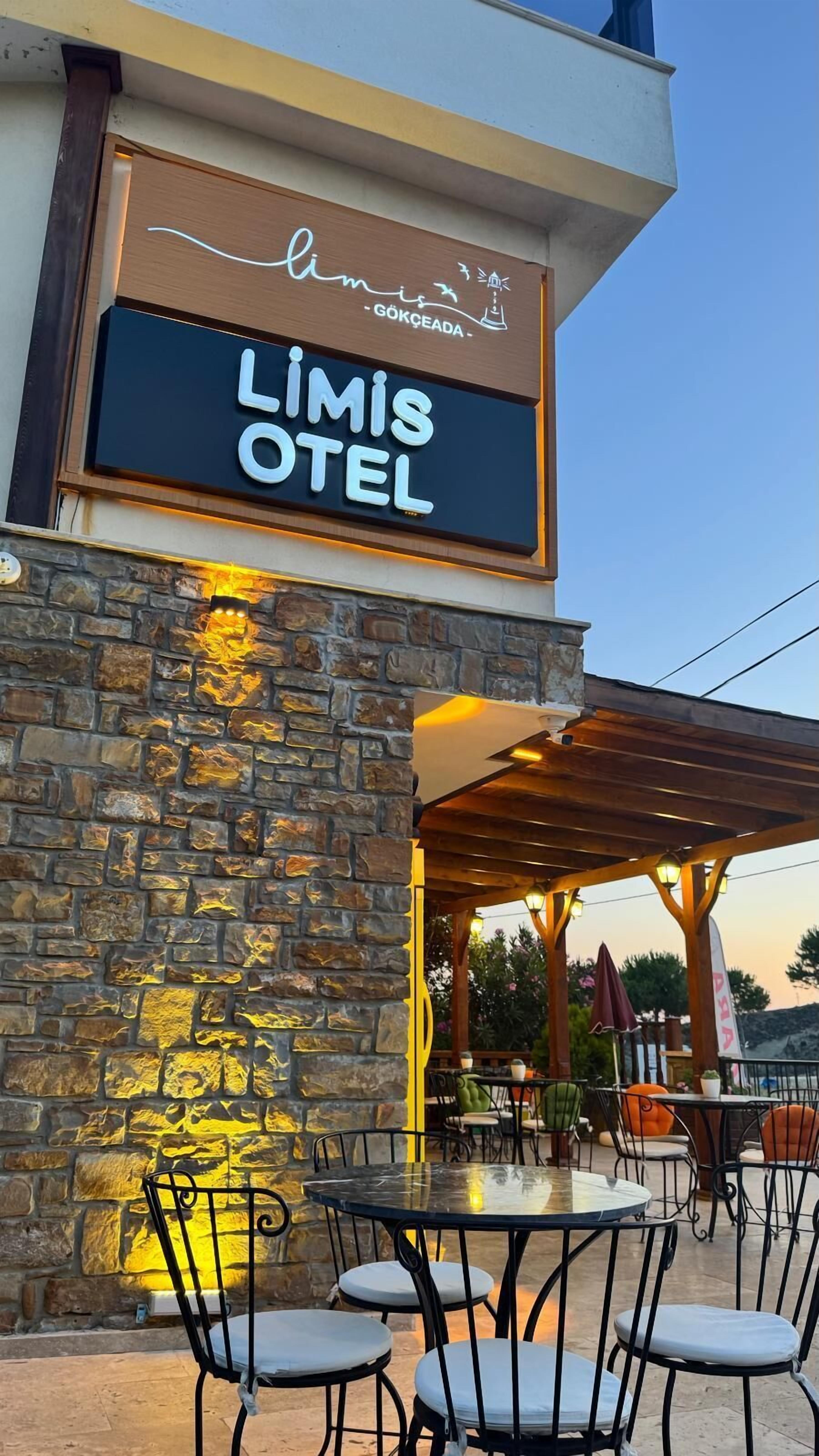 An outdoor seating area with stone walls and metal chairs at Limis Hotel.