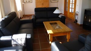 A living room with a black sofa, a wooden coffee table, and a fireplace.