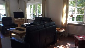 A living room with a sofa, a TV, and a window with curtains.