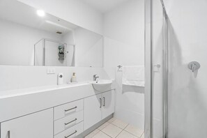 Een moderne badkamer met een grote spiegel, een wastafel en een douchehoek.