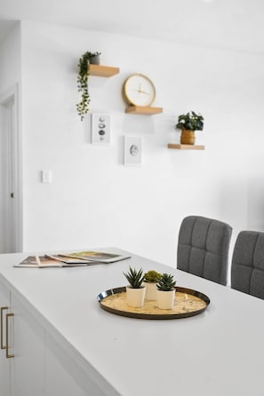 Een moderne keuken met witte kastjes, een marmeren aanrechtblad en een rond dienblad met potplanten.