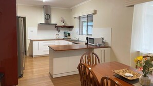 A compact kitchen with white cabinetry, a wooden dining table, and a microwave.
