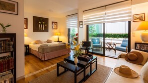 Une chambre d’hôtel comprenant un lit, une table basse, un canapé, une télévision et un balcon avec des sièges d’extérieur.
