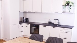 A modern kitchen with white cabinets, a black countertop, a built-in oven, and a sink. - Kürzlich Renovierte 3-bett-ferienwohnung mit Garten und Blick auf den Gletscher (Kaprun)