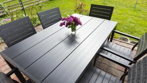 A rectangular outdoor table with a vase of purple flowers, surrounded by black chairs. - Kürzlich Renovierte 3-bett-ferienwohnung mit Garten und Blick auf den Gletscher (Kaprun)