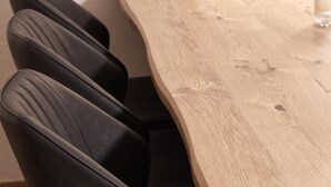 A wooden dining table with a curved edge and black upholstered chairs. - Kürzlich Renovierte 3-bett-ferienwohnung mit Garten und Blick auf den Gletscher (Kaprun)