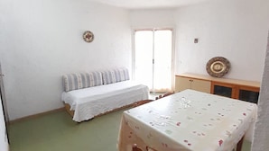 Um quarto pequeno e simples, com uma cama, uma mesa e um banco.
