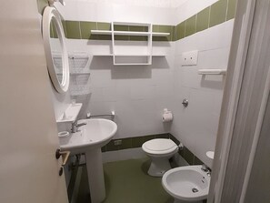 A small bathroom with a sink, toilet, bidet, and a mirror. - Belvilla by OYO Apartment in Golfo Aranci (Golfo Aranci)