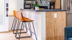 A compact kitchen with wooden cabinets, a built-in microwave, and a stainless steel refrigerator. - Swanky Studio in Vibrant Hillcrest (San Diego)