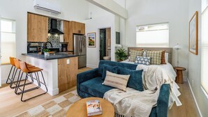 A compact living space with a kitchenette, a sofa, a coffee table, and a bed. - Swanky Studio in Vibrant Hillcrest (San Diego)
