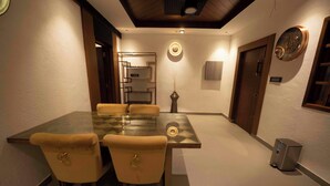 Une salle de conférence avec une table en verre et quatre chaises, une horloge au mur et une poubelle.