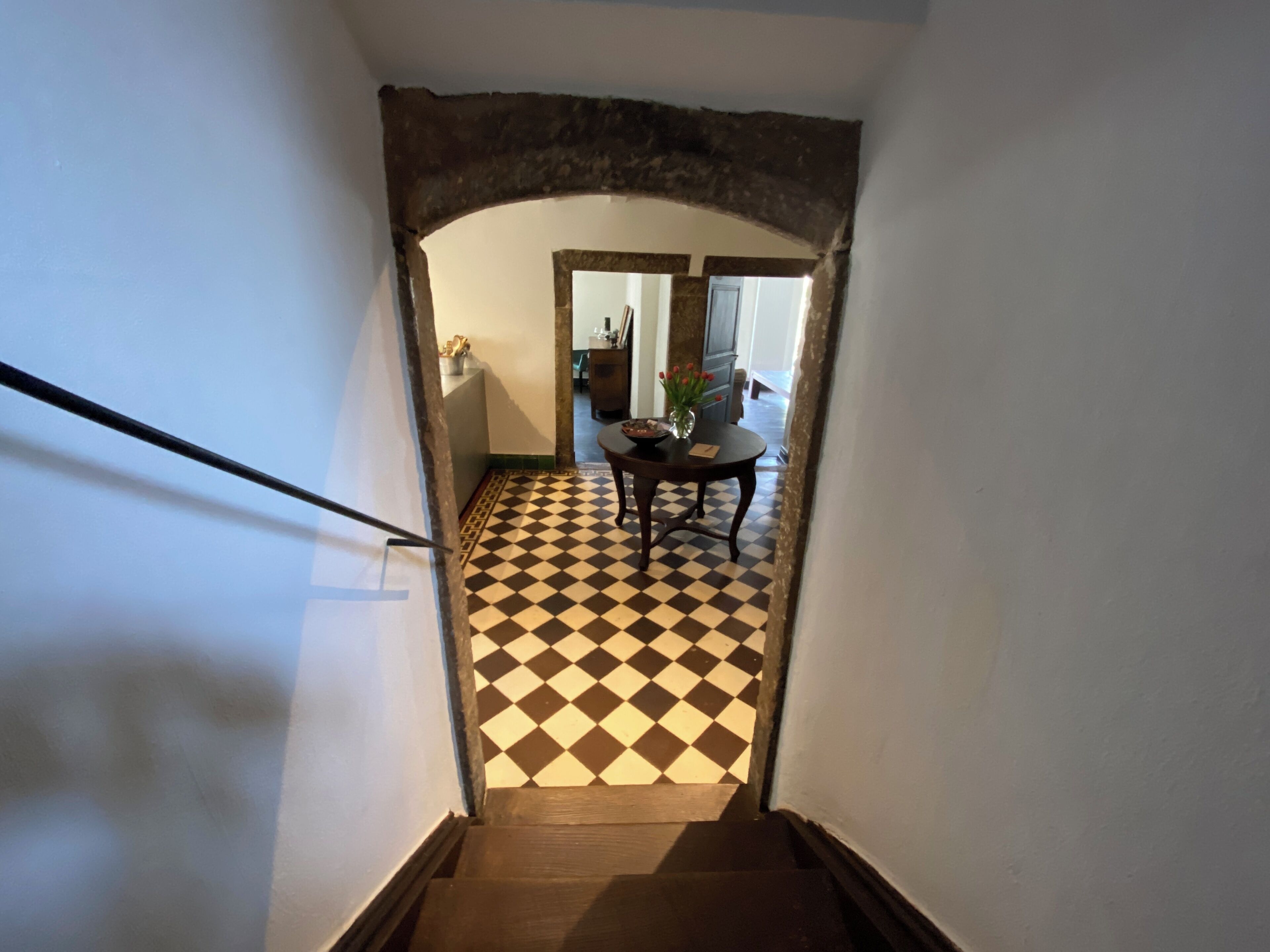 A staircase leading to a dining area with a checkered floor and a table with chairs.