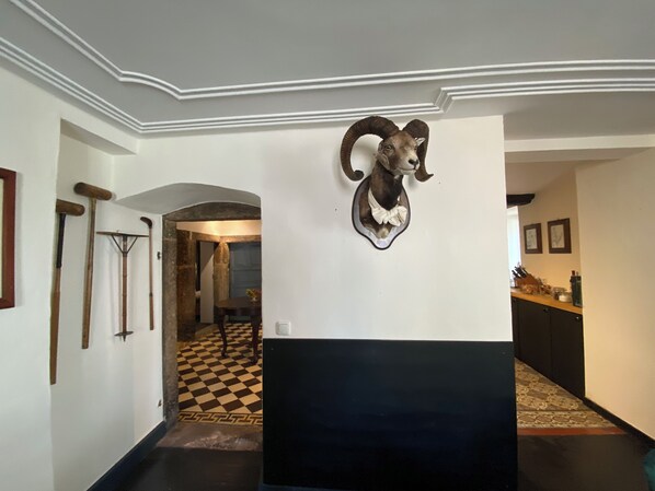 A hallway with a mounted ram head decoration, a checkered floor, and a doorway leading to another room. - Holidayhouse Countryside 'Un der Attert' (Helperknapp)