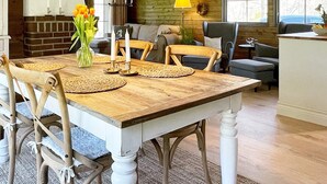Een eetruimte met een houten tafel, stoelen en een bloevas.